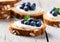 Toasts with berry cream cheese, fresh blueberries, toasted almonds