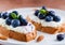 Toasts with berry cream cheese, fresh blueberries, toasted almonds