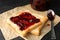 Toasts and glass jar with jam, spoon and baking paper on black background