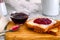 Toasts with jam on wooden board and bowl with jam on kitchen table