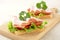 Toasts,lettuce,tomato,cold cuts on cutting board on linen tablecloth
