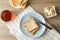 Toasts on plate, towel, tea and butter on background, top view