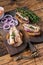 Toasts with sardine, cream cheese and onion. Wooden background. Top view