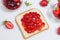 Toasts with strawberry jam for breakfast on white rusric wooden background. Top view