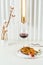 Tobacco chicken on a beautiful background with a glass of red wine, a vase with cotton twigs and a stylish lamp.