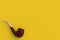 Tobacco pipe in corner on yellow background