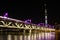 Tobu Railway bridge over Sumida River lit up in purple below illuminated Tokyo Skytree at night