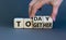 Today we are together symbol. Businessman turns wooden cubes and changes the word together to today. Beautiful grey background,