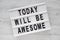 `Today will be awesome` words on modern board over white wooden surface, overhead view.