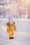 Toddler 12-17 months in a yellow jacket stands in a snowy winter park