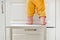 Toddler baby boy climbed with his feet on a high chair to climb on the kitchen cabinet. Child safety issues in the home room,