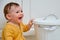Toddler baby boy opens a trash can with household waste. Children`s safety issues in the home room, little kid
