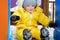 Toddler baby boy in a yellow snowsuit rides down a children slide on a