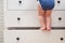 Toddler baby climbed up on the open chest of drawers. Child boy stood