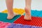 Toddler on baby foot massage mat. Exercises for legs on orthopedic massage carpet. prevention of flat feet and hallux valgus