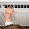 Toddler baby holding on to the radiator, child hand on the heating syste