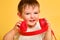 Toddler baby listens to music in red headphones on a studio yellow ba