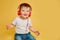 Toddler baby listens to music in red headphones on a studio yellow ba