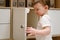 Toddler baby opens the closet door in the home living room. A small ch