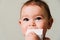 Toddler baby teething with white toy, close up portrait of childhood