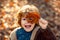 Toddler boy in autumn park. Child covers his eyes with a yellow maple leaf in the autumn park. Kids walking in autumn