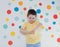 Toddler boy on a background of wall with colorful circles. Boy giving thumbs down