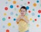 Toddler boy on a background of wall with colorful circles. Boy giving thumbs up
