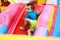 Toddler boy in blue shirt and yellow shorts climbing up slide on bright inflatable bouncy castle and looking away