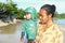 Toddler boy carried by his mom on the beach by sea