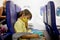Toddler boy, child boarding on the airplane, sitting and waiting for departure, playing with toys