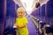 Toddler boy, child boarding on the airplane, standing on the aisle between the rows of seats