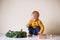 A toddler boy and a Christmas wreath on a table.