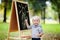 Toddler boy drawing standing by a blackboard