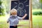 Toddler boy drawing standing by a blackboard