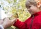 Toddler boy on a farm meets a gosling chick, which is held by an adult`s hands