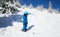 Toddler boy in helmet, glasses and blue winter coveralls on skis in snow-capped mountains