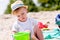 Toddler boy playing with sand sifter on a beach