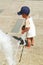 Toddler boy playing with small pots in water of fountain