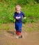 Toddler boy playing in water puddles