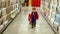 Toddler boy pulls shopping cart and looking around walking through hardware store.