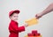 toddler boy in red overalls and cap passes yellow postal envelope to hand of adult