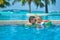 Toddler boy in resort pool with father