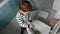 Toddler boy shows how he washes the toilet with a liquid soap.