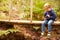 Toddler boy sitting alone on a wooden bridge in a forest