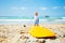 Toddler boy stand pull surfboard to the sea waves