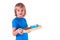 Toddler boy standing with a tray of Montessori materials for a lesson on a white background. Exercise cutting with scissors.