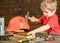 Toddler on busy face plays with hammer tool at home in workshop. Handcrafting concept. Kid boy play as handyman. Child