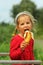 Toddler caucasian girl enjoying eating  banana outdoor