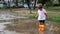 Toddler child in orange boots walks through the puddles after the rain