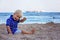 Toddler child, sitting on beach, watching lighted ship in the ocean